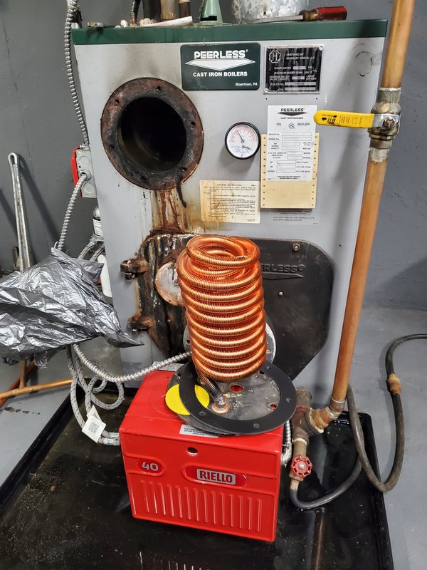 New copper tankless coil resting on the burner before fitting